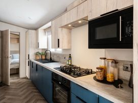 A kitchen with sink and stove at Rowan Waterside Spa Carlton Miniott near Thirsk