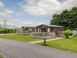 Two wooden chalets with decking in an outdoor area at Alder Spa in Carlton Miniott near Thirsk