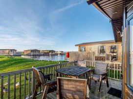 An outdoor area with a table and chairs near water at Alder Waterside Spa Carlton Miniott near Thirsk