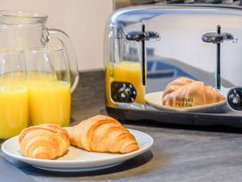 A kitchen countertop with a toaster, croissants, and glasses of orange juice at Cedar in Carlton Miniott near Thirsk