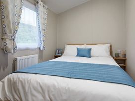 A bedroom with a bed and side table at Banyan Waterside Spa Carlton Miniott near Thirsk