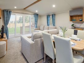 A living room with a dining area and exit to outdoor space at Banyan Waterside Spa in Carlton Miniott near Thirsk