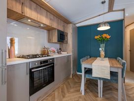 A kitchen with a gas stove and dining table at Ellery Waterside Spa in Carlton Miniott near Thirsk
