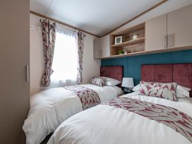 A bedroom with two beds and a shelf at Ellery Waterside Spa Carlton Miniott near Thirsk
