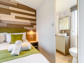 A bedroom with a bed and an attached bathroom at Cedar Spa in Carlton Miniott near Thirsk