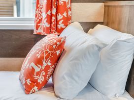 A bed with white pillows and an orange patterned cushion at Kinder Spa Carlton Miniott near Thirsk