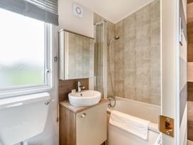 A bathroom with a shower, bath tub, sink, and toilet at Kinder Spa (Pet) Carlton Miniott near Thirsk