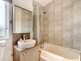 A bathroom with a bathtub, sink, and shower at Kinder Spa (Pet) Carlton Miniott near Thirsk