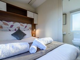A bedroom with a bed and bathroom in Alder Waterside Spa (Pet) Carlton Miniott near Thirsk