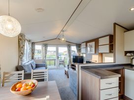 A living room with a sofa and dining table at Alder Waterside Spa (Pet) Carlton Miniott near Thirsk