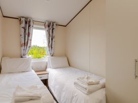 A bedroom with twin beds and a window at Oak Waterside Spa Carlton Miniott near Thirsk