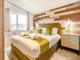 A bedroom with a bed and nightstand at Oak Waterside Spa Carlton Miniott near Thirsk