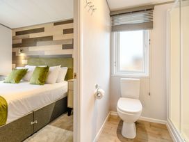 A bedroom with a bed and a toilet area at Oak Waterside Spa, Carlton Miniott near Thirsk