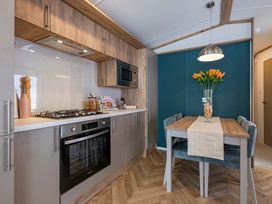 A kitchen with modern appliances and a dining table at Redwood Waterside Spa Carlton Miniott near Thirsk
