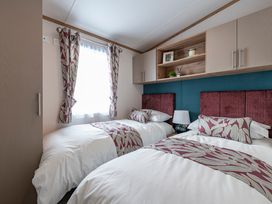 A bedroom with two beds and shelves at Redwood Waterside Spa in Carlton Miniott near Thirsk
