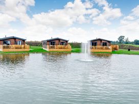 Three cabins next to a pond with a fountain at Spindle Spa (Pet) Carlton Miniott near Thirsk