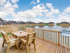 An outdoor area with a table and chairs overlooking a water body at Spindle Spa (Pet) Carlton Miniott near Thirsk