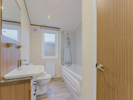 A bathroom with a bath tub, toilet, and sink at Larch Waterside Spa in Carlton Miniott near Thirsk
