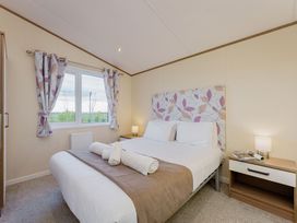 A bedroom with a bed and window at Larch Waterside Spa Carlton Miniott near Thirsk