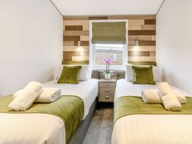 A bedroom with twin beds and a nightstand at Beech Waterside Spa Carlton Miniott near Thirsk