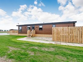A log cabin with deck and fenced outdoor area at Beech Waterside Spa (Pet) Carlton Miniott near Thirsk