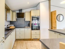 A kitchen with cabinets, sink, and appliances at Beech Waterside Spa (Pet) Carlton Miniott near Thirsk