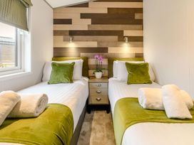 A bedroom with two beds and a nightstand at Beech Waterside Spa (Pet) Carlton Miniott near Thirsk