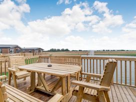 An outdoor area with wooden deck furniture at Beech Waterside Spa (Pet) Carlton Miniott near Thirsk