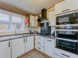 A kitchen with a sink, kettle, gas stovetop, and ovens at Larch Waterside Spa (Pet) Carlton Miniott near Thirsk