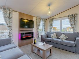 A living room with a sofa and television at Larch Waterside Spa (Pet) Carlton Miniott near Thirsk