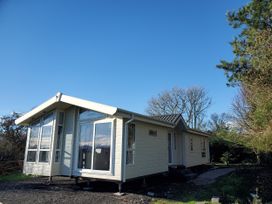 A house with large windows and a pathway at Plas Marchog Lodge in Pentraeth