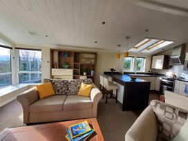 A living room with a sofa and kitchen area at Plas Marchog Lodge in Pentraeth