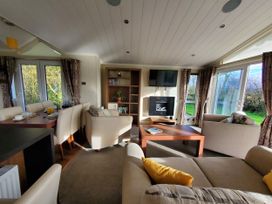 A living room with a sofa and dining table at Plas Marchog Lodge in Pentraeth