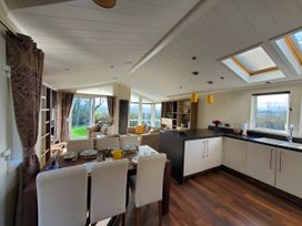 A living room and kitchen area with dining table and sofas at Plas Marchog Lodge in Pentraeth