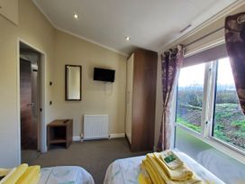 A bedroom with a mirror and television at Plas Marchog Lodge in Pentraeth