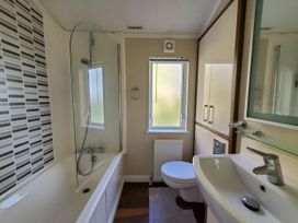 A bathroom with bathtub and shower at Plas Marchog Lodge in Pentraeth