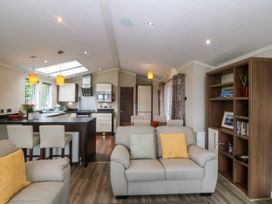 A living room with sofa and kitchen island at Plas Marchog Lodge Rhoscefnhir near Pentraeth