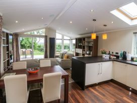 A living room with sofa and dining area at Plas Marchog Lodge Rhoscefnhir near Pentraeth