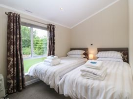 A bedroom with two beds and a window at Plas Marchog Lodge Rhoscefnhir near Pentraeth