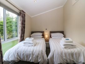 A bedroom with twin beds and a lamp at Plas Marchog Lodge Rhoscefnhir near Pentraeth