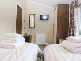 A bedroom with two beds and a television at Plas Marchog Lodge Rhoscefnhir near Pentraeth