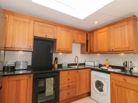 A kitchen with wooden cabinets and appliances at Daisy Bank in Maugersbury near Stow-On-The-Wold
