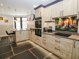 A kitchen with wooden cabinets and a cooktop at Cragg Cottage in Coniston