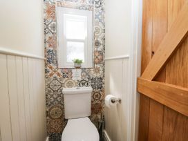 A bathroom with a toilet and patterned wall tiles at Cragg Cottage in Coniston