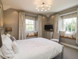 A bedroom with a bed, nightstand, and window seats at Cragg Cottage in Coniston