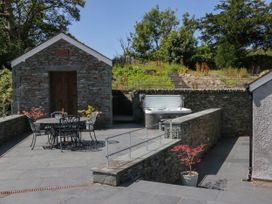 An outdoor area with a stone building, table and chairs, hot tub at Cragg Cottage in Coniston