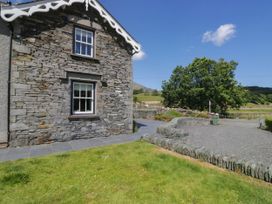 An outdoor view of a stone house with a window at Cragg Cottage in Coniston