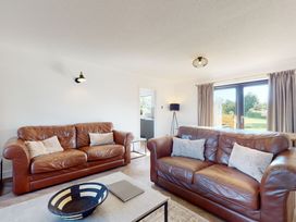 A living room with two leather sofas and a table at Low Greenlands House in Tewitfield