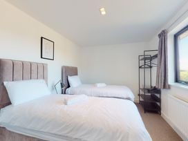 A bedroom with two beds and a clothes rack at Low Greenlands House in Tewitfield