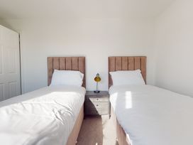 A bedroom with two single beds and a nightstand at Low Greenlands House in Tewitfield